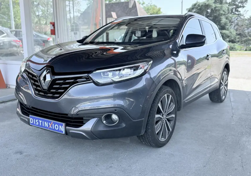 Renault Kadjar gris en vue 3/4 avant droit, avec calandre noire et jantes alliage visibles.