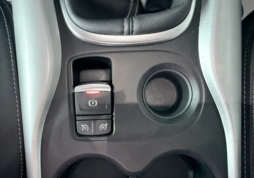 Gros plan sur la console centrale noire du Renault Kadjar gris, avec frein à main électronique et porte-gobelets.