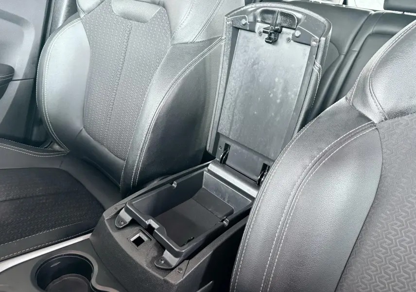 Vue rapprochée de l’intérieur du Renault Kadjar gris, montrant l’accoudoir central ouvert entre les sièges avant en tissu et cuir noir.
