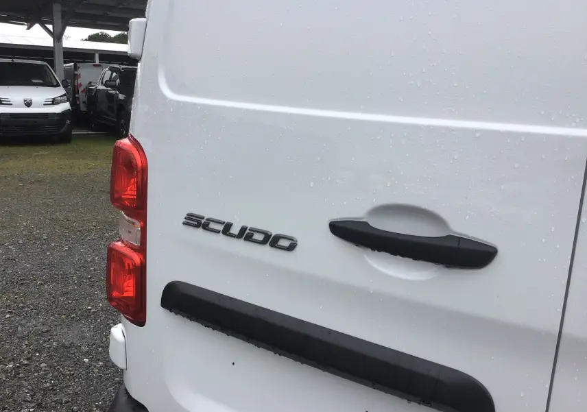 Gros plan sur l’arrière gauche blanc du FIAT Scudo Fourgon 2024, avec poignée noire et feux rouges visibles sous la pluie.