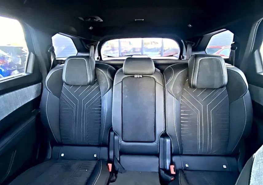 Vue arrière intérieure sur les sièges noirs du rang 2 du Peugeot 5008 Hybrid 145 GT avec appuis-tête et surpiqûres.