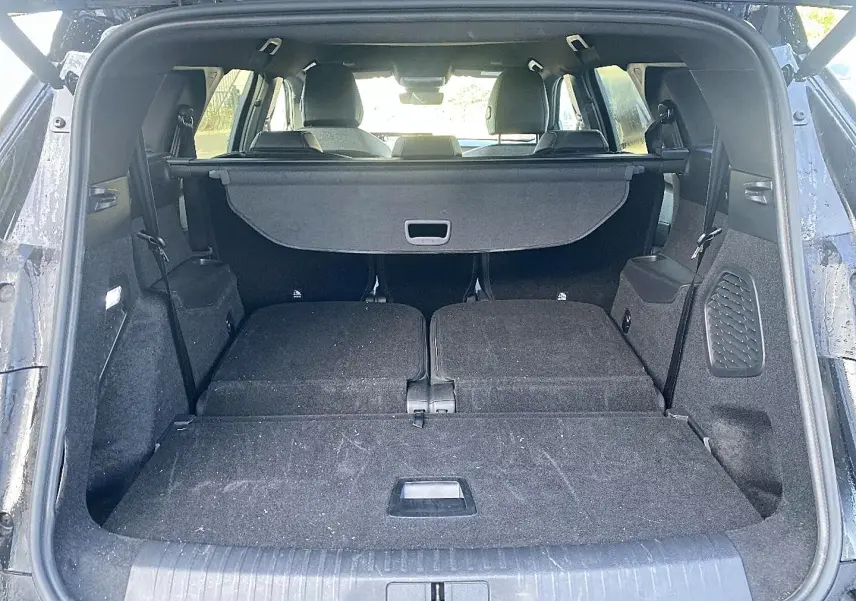 Coffre ouvert d’un Peugeot 5008 noir, vue arrière montrant les sièges rabattus et le cache-bagages déployé.
