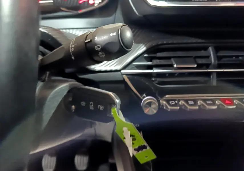 Gros plan intérieur sur la colonne de direction et tableau de bord noir de la Peugeot 208 2020, version BlueHDi Active Business.