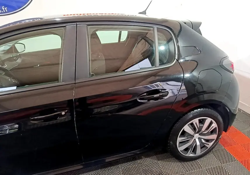 Vue de profil côté droit d'une Peugeot 208 noire, mettant en valeur les jantes et la ligne arrière du véhicule.