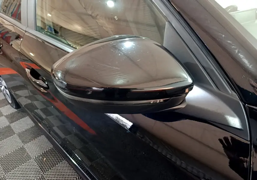 Vue rapprochée du rétroviseur droit noir brillant d'une Peugeot 208 2020, avec portière et poignée visibles.