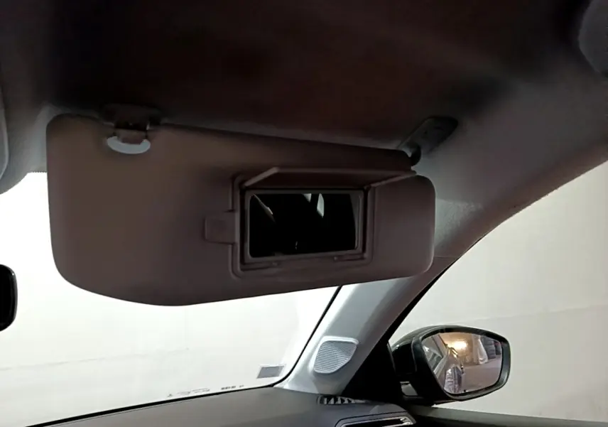 Vue intérieure côté gauche sur le pare-soleil avec miroir ouvert d’une Peugeot 208 noire de 2020.