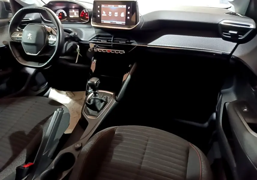 Vue intérieure avant droite du tableau de bord noir de la Peugeot 208 avec écran tactile et volant cuir multifonctions.