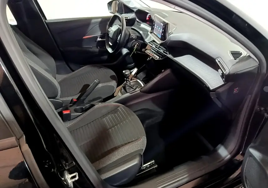 Intérieur de la Peugeot 208 noir vue côté conducteur, avec tableau de bord moderne et écran tactile central.
