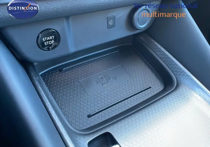 Gros plan sur la console centrale noire du Nissan Qashqai 2025, montrant le bouton Start/Stop et un espace de recharge sans fil.