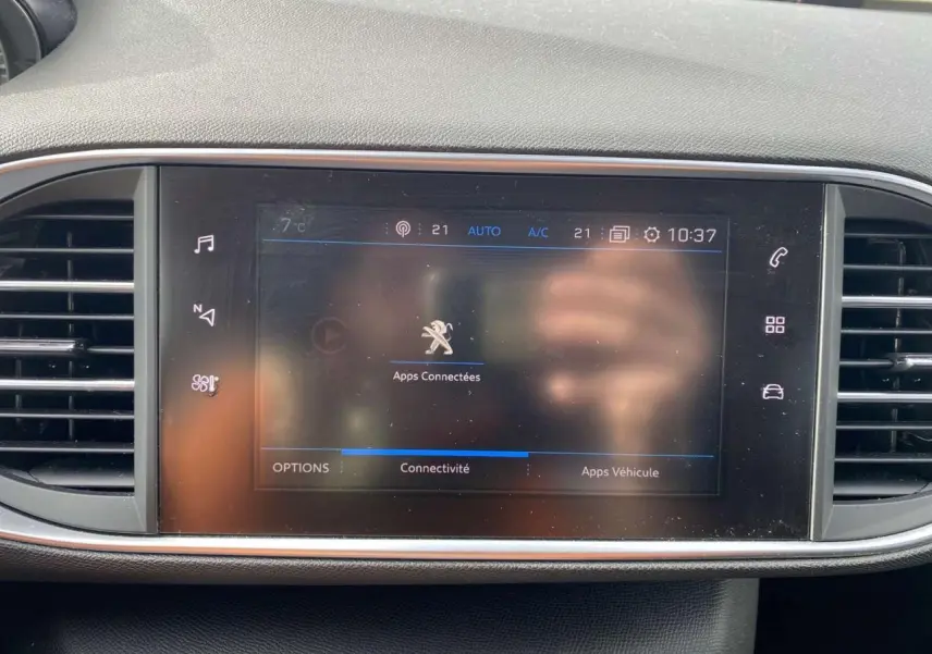 Vue rapprochée de l’écran tactile central du tableau de bord d’une Peugeot 308 bleu foncé, affichant les apps connectées.