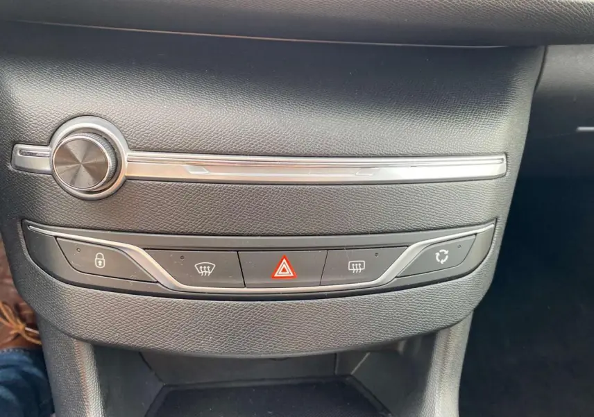 Gros plan sur la console centrale noire de la Peugeot 308 2018, avec boutons de verrouillage et feux de détresse rouges.