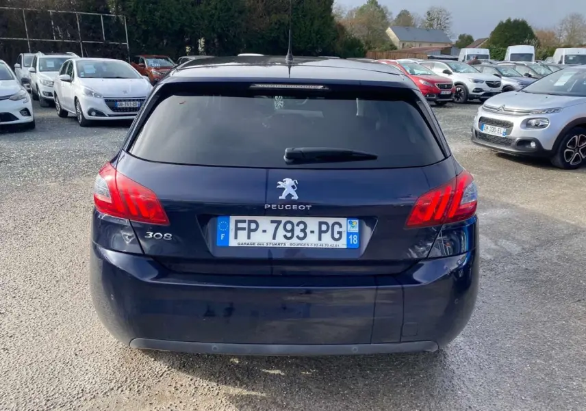 Vue arrière d'une Peugeot 308 2018 bleu foncé avec feux arrière allumés et plaque d'immatriculation visible.
