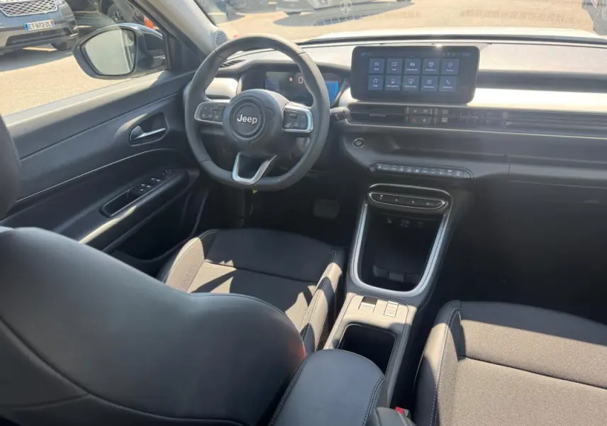Intérieur du Jeep Avenger électrique 2025 vu côté conducteur, avec volant cuir, écran tactile et console centrale noire.