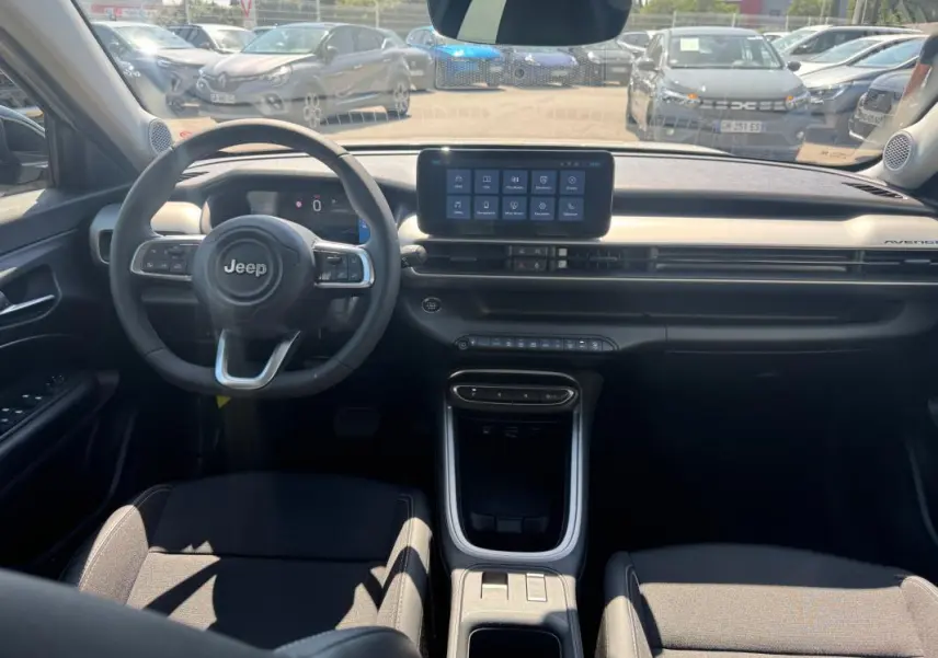 Vue intérieure avant du Jeep Avenger électrique 2025, tableau de bord moderne avec écran tactile central et volant cuir.