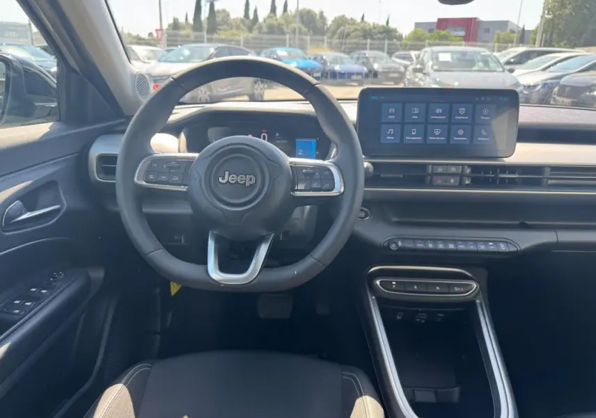 Vue intérieure frontale du tableau de bord et volant cuir du Jeep Avenger électrique blanc 2025 avec écran tactile central.