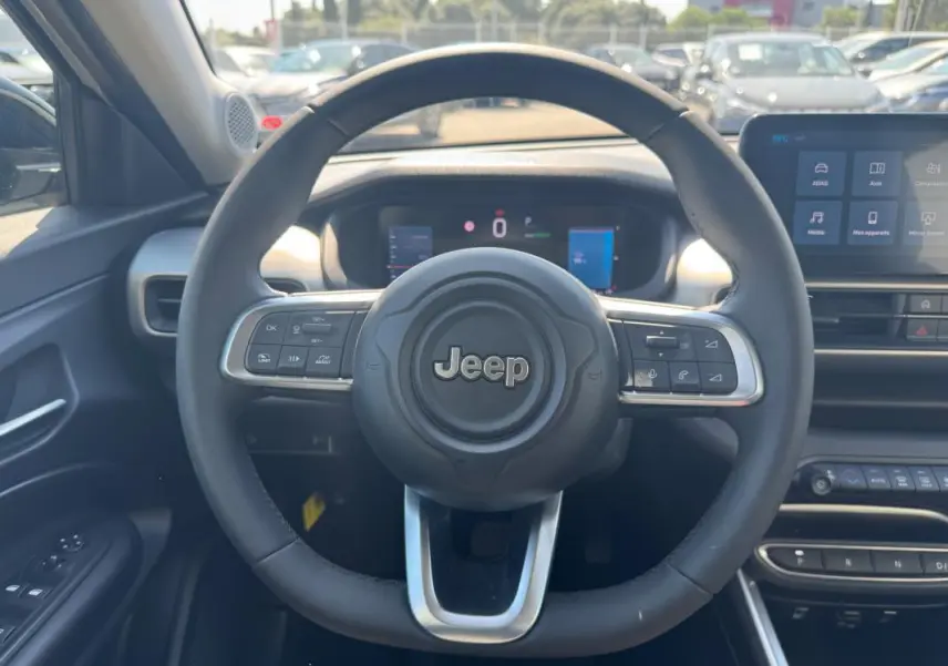 Vue intérieure centrée sur le volant cuir du Jeep Avenger électrique 2025 avec tableau de bord numérique et écran tactile.