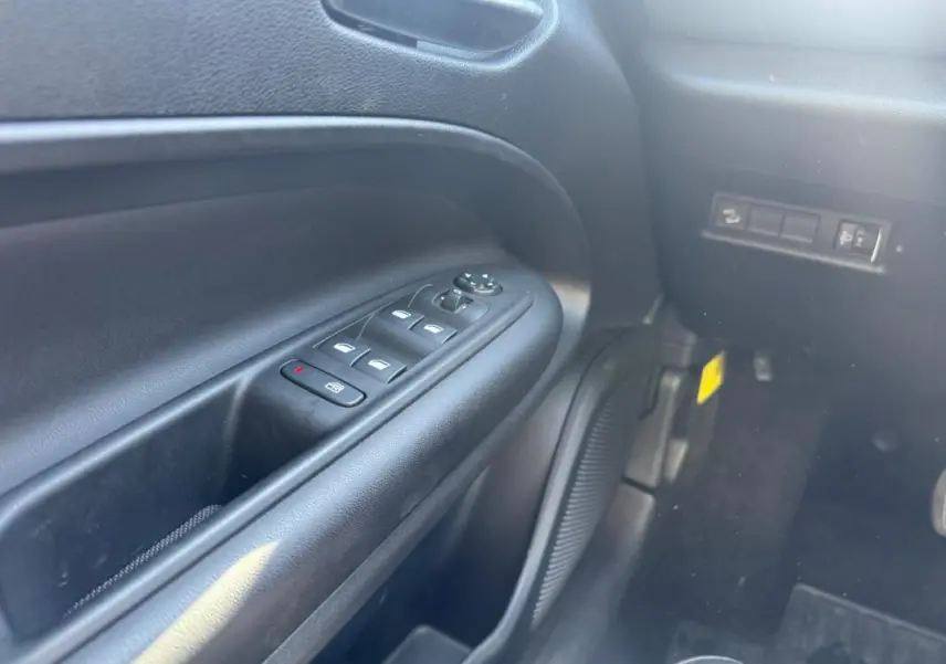 Gros plan sur le panneau de commandes des vitres électriques côté conducteur du Jeep Avenger 2025, intérieur noir.