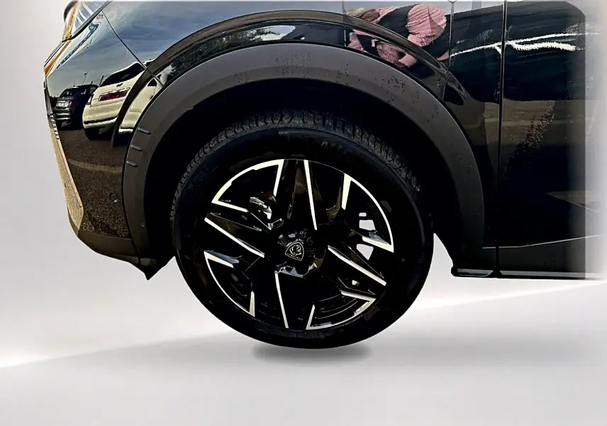 Gros plan sur la roue avant gauche noire avec jante alu noire et argent du Peugeot 5008 Hybrid 145 GT e-DCS6 noir.