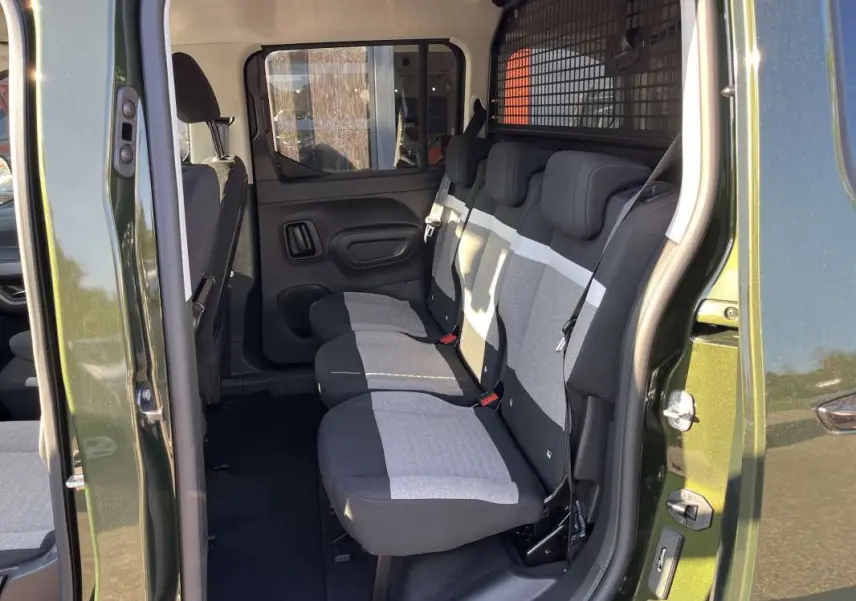 Vue latérale intérieure du Citroën Berlingo Sirkka green montrant les trois sièges arrière indépendants et la grille de séparation.