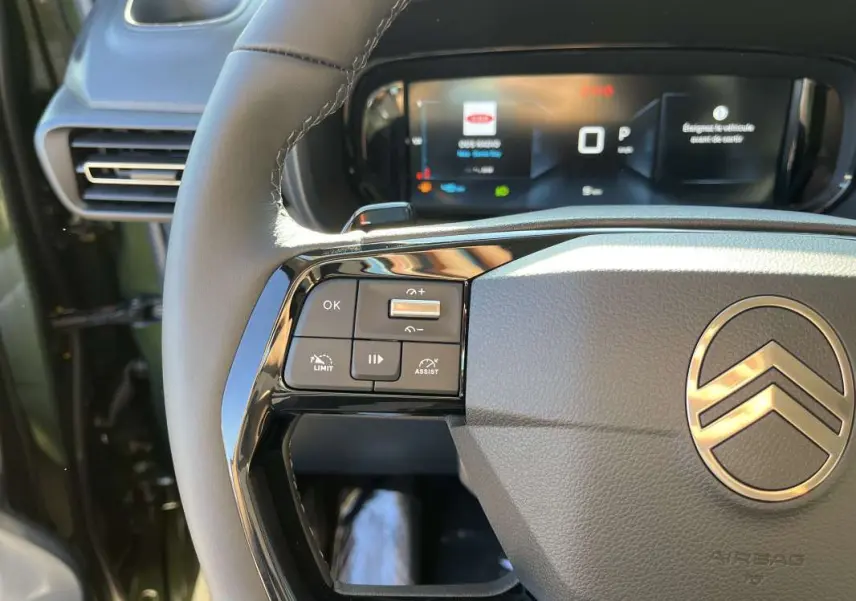 Gros plan sur le volant cuir gris du Citroën Berlingo Sirkka green 2026 avec commandes multifonctions et tableau de bord numérique.