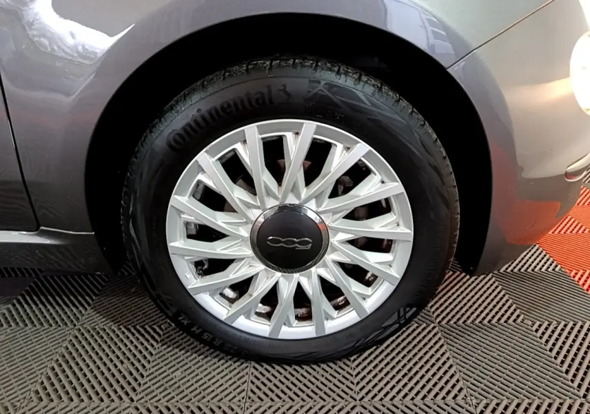 Gros plan sur la roue avant droite gris foncé d'une FIAT 500 1.0 70ch BSG Dolcevita avec jante argentée à rayons fins.
