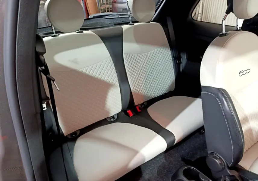 Vue intérieure de la banquette arrière beige et noire du FIAT 500 1.0 70ch BSG Dolcevita, avec siège avant partiellement visible.