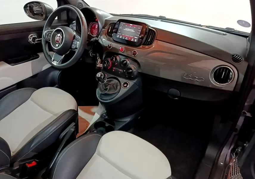 Vue intérieure côté conducteur de la Fiat 500 1.0 gris foncé avec tableau de bord brillant et volant cuir multifonctions.