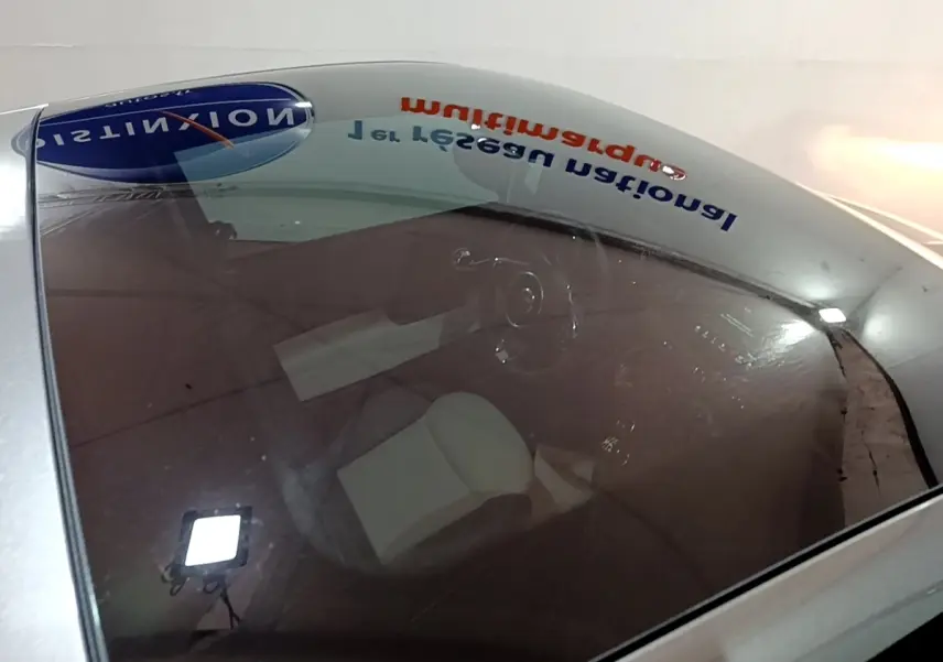 Vue plongeante sur l'intérieur d'une FIAT 500 gris foncé, volant cuir et sièges clairs visibles à travers le pare-brise.