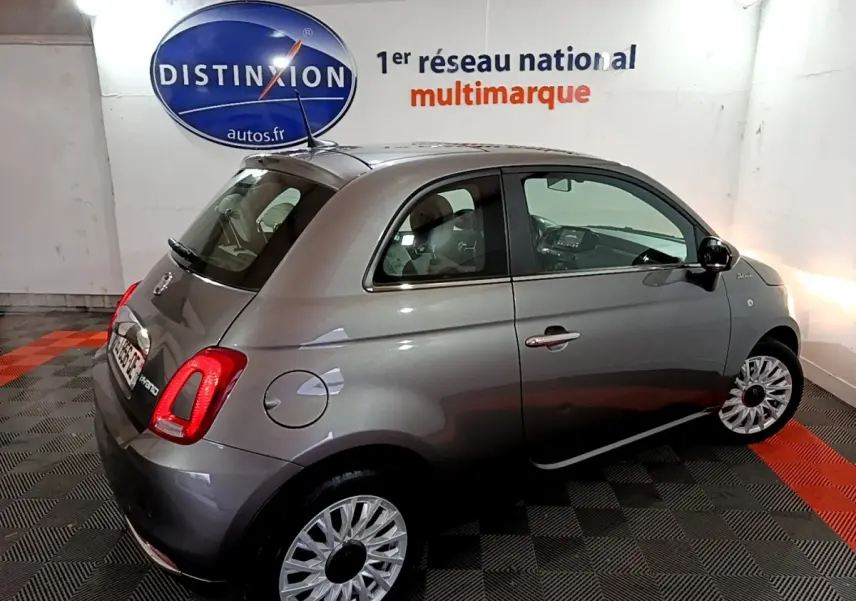 Vue 3/4 arrière droite d'une FIAT 500 gris foncé, avec jantes multibranches et feux arrière LED visibles.