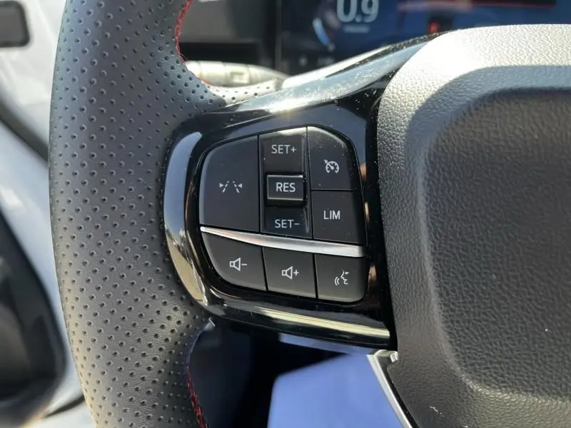 Gros plan sur les commandes de régulateur de vitesse et volume au volant perforé du Ford Puma blanc 2025, version ST-Line X.