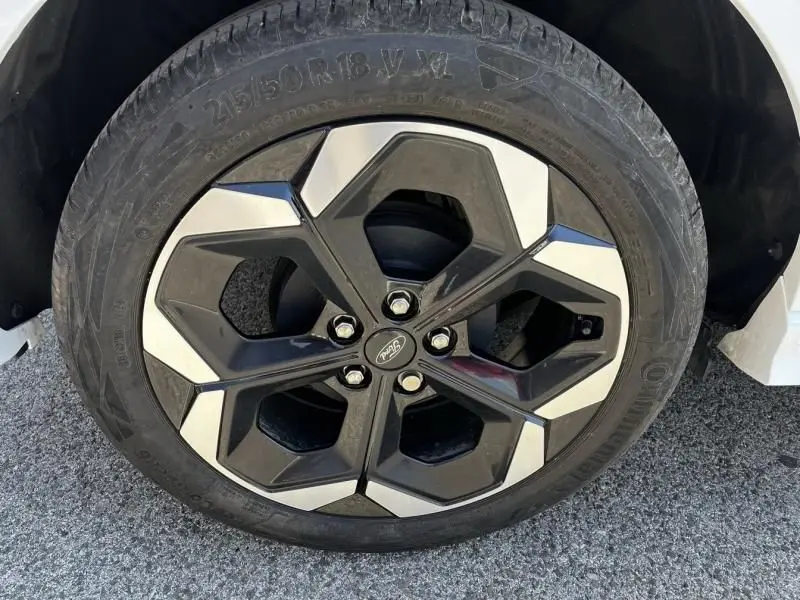 Gros plan sur la roue avant droite du Ford Puma blanc 2025, jante alliage noire et argentée au design hexagonal.