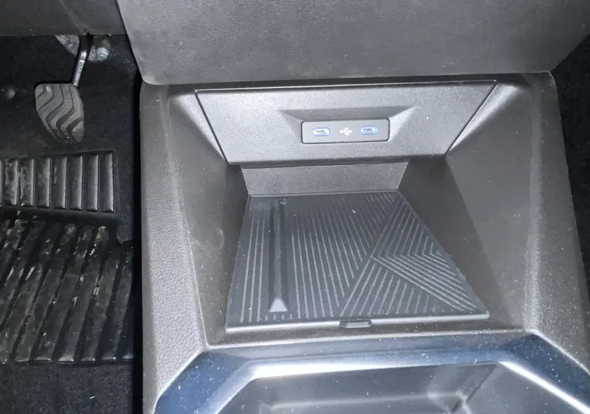 Gros plan sur la console centrale de la Renault Clio VI gris Rafale, montrant les ports USB et le tapis antidérapant.