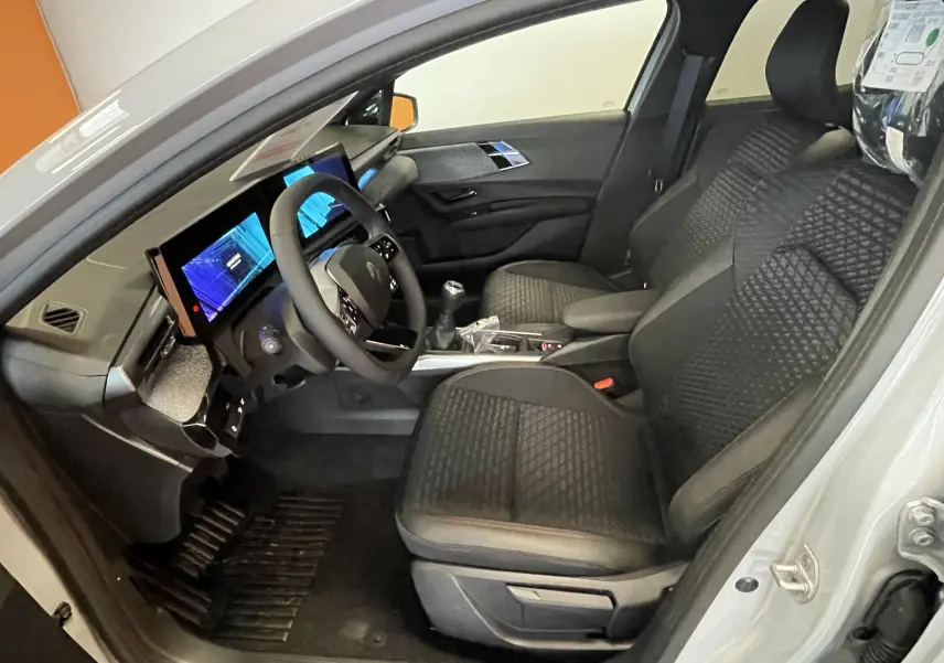 Vue intérieure côté conducteur de la Renault Clio VI TCE 115ch Techno gris Rafale, sièges noirs et tableau de bord digital.