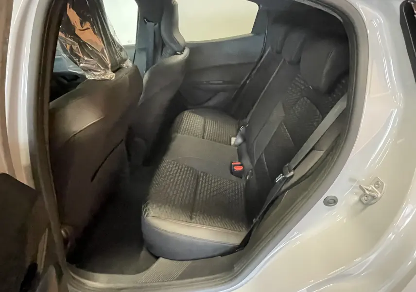 Vue intérieure arrière côté droit de la Renault Clio VI TCE 115ch Techno, sièges noirs avec tissu texturé et ceinture de sécurité.