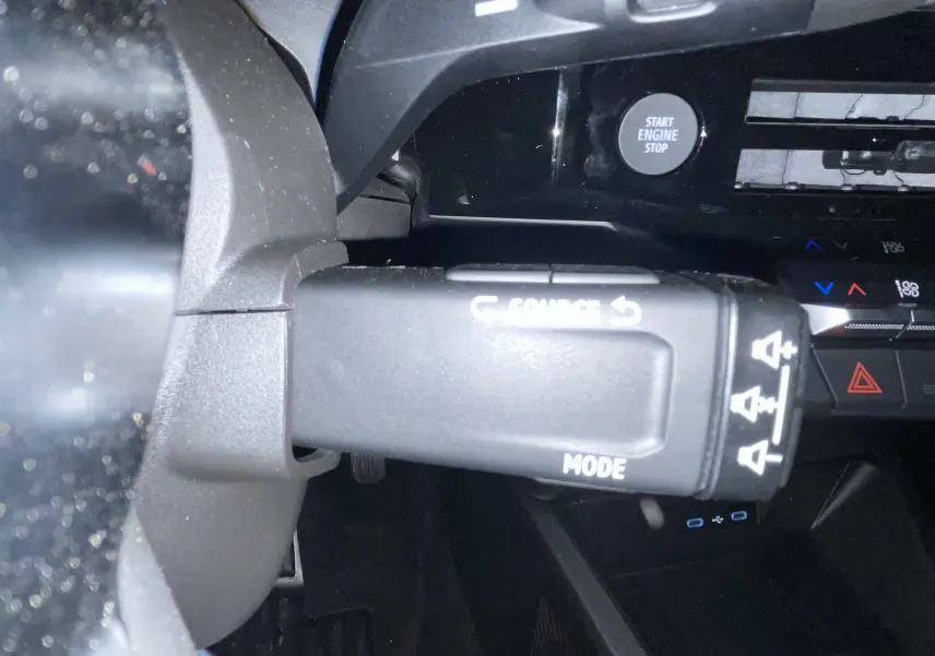 Gros plan sur la commande multimédia à gauche du volant d'une Renault Clio gris Rafale, avec bouton start engine stop visible.