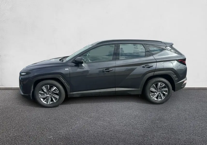 Vue de profil côté gauche d'un Hyundai Tucson gris 2023, version hybride diesel avec jantes alliage et lignes anguleuses marquées.