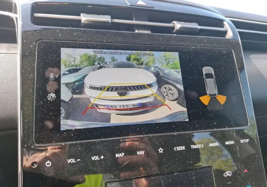 Affichage de la caméra de recul montrant un Hyundai Tucson gris de face, avec guidage de trajectoire sur l'écran intérieur.