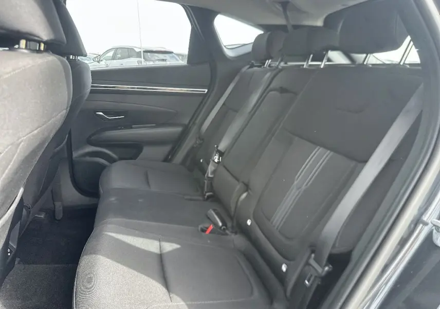 Vue intérieure côté droit des sièges arrière noirs du Hyundai Tucson 2023 gris, montrant l'espace et les appuie-têtes réglables.