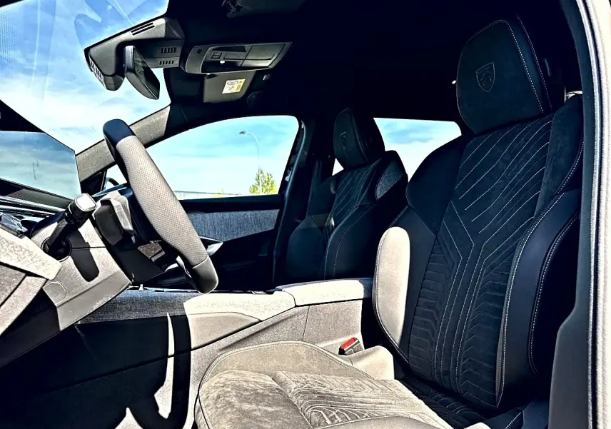 Vue intérieure côté conducteur du Peugeot 5008 Hybrid 145 GT e-dcs6 2025, sièges noirs avec surpiqûres et logo Peugeot.