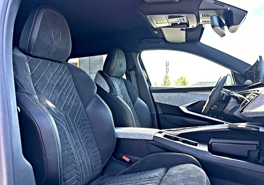 Intérieur avant du Peugeot 5008 Hybrid 145 GT 2025, sièges noirs en cuir et alcantara avec surpiqûres blanches.