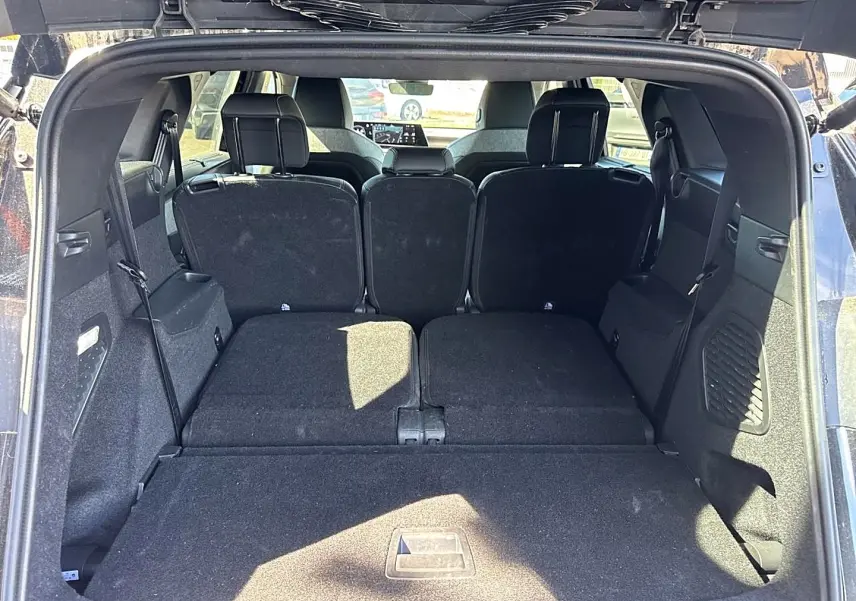 Vue arrière du coffre ouvert du Peugeot 5008 noir avec banquette arrière partiellement rabattue et espace de chargement plat.