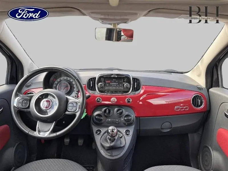 Vue intérieure avant du tableau de bord rouge brillant et volant cuir noir de la FIAT 500 noire, édition Rosso Amore.