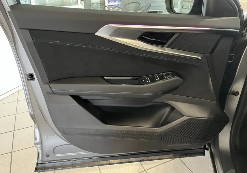 Intérieur de la porte avant gauche du Renault Austral 2025 gris, avec éclairage d’ambiance violet et finitions Alcantara.
