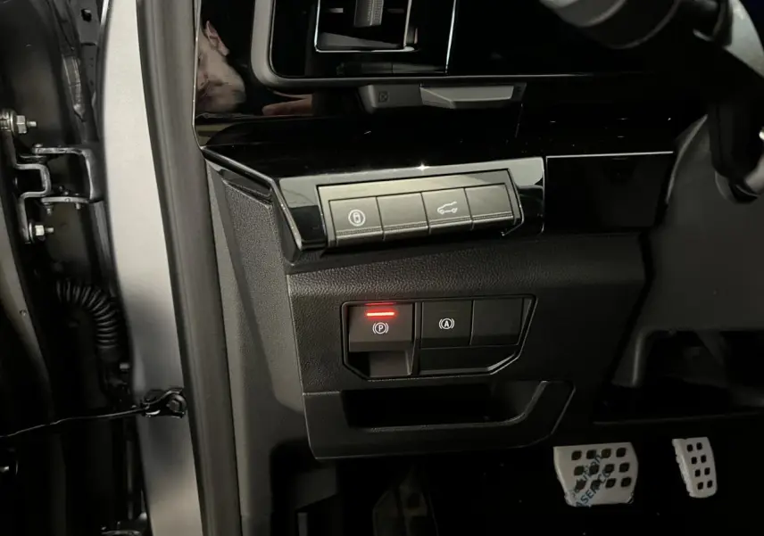 Gros plan sur les commandes noires côté gauche du tableau de bord d’un Renault Austral gris, avec pédalier aluminium.