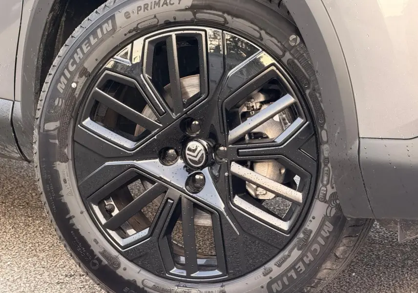 Gros plan sur la roue avant droite d’une Citroën C4 hybride gris Mercury avec jante noire et argentée au design géométrique.