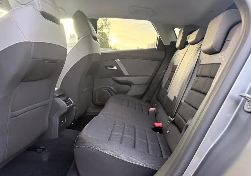 Vue intérieure côté droit des sièges arrière noirs et gris du Citroën C4 hybride 2025 en gris Mercury, avec ceinture et appuie-têtes visibles.