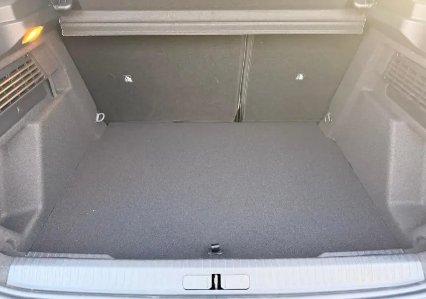 Coffre ouvert du Citroën C4 hybride gris Mercury, vue de l’arrière montrant un espace de chargement propre et spacieux.