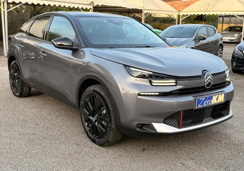 Citroën C4 hybride gris Mercury en 3/4 avant droit, avec jantes noires et signature lumineuse LED distinctive.