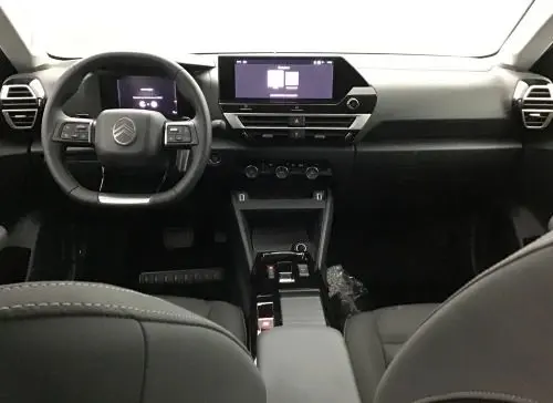 Vue intérieure avant du Citroën C4 Hybride 145 E-DCS6 Collection 2025, tableau de bord noir avec écran tactile central et volant multifonction.