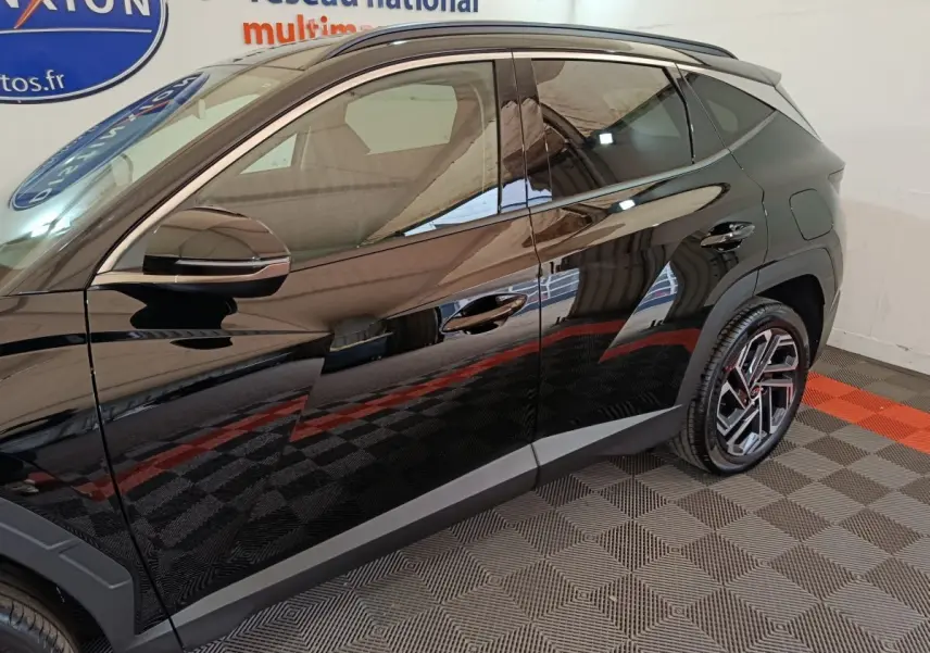 Vue latérale côté gauche du Hyundai Tucson 1.6 Hybrid noir 2025 avec jantes alliage et rétroviseur chromé.